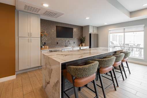 A kitchen with a marble countertop and bar stools.
