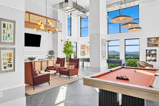 A pool table is in the middle of a room with a television, couches, and pictures on the wall.