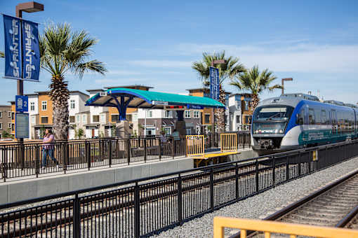 A train is pulling into a station with a blue canopy.