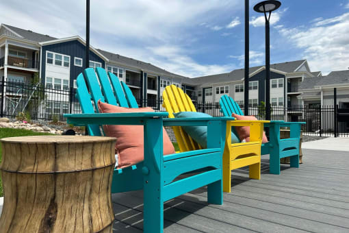 chairs and tables on a deck in front of apartment buildings