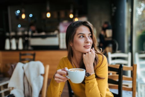 a woman sitting in a restaurant holding a cup of coffee