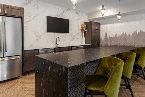 A kitchen with a marble countertop and green chairs.