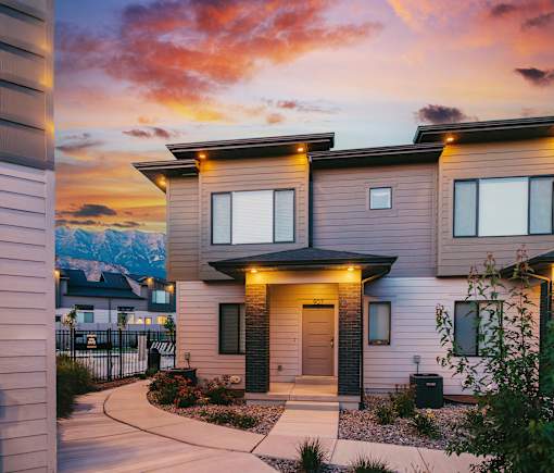 A modern house with a front yard and a mountain in the background.