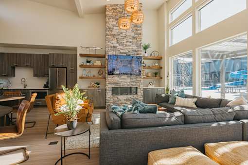 A living room with a grey couch and a stone fireplace.