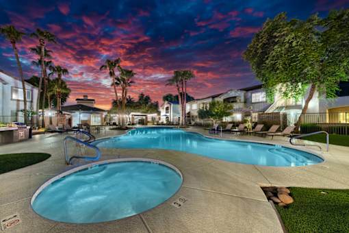 A large outdoor swimming pool surrounded by palm trees and lounge chairs.
