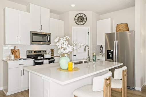 A white kitchen with a clock on the wall at Coral Palms at Oakleaf townhomes in Middleburg, Florida.