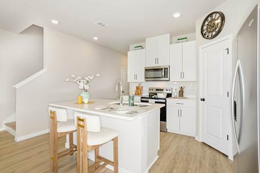A kitchen with white cabinets and a wooden table at Coral Palms at Oakleaf townhome rentals in Middleburg, Florida.