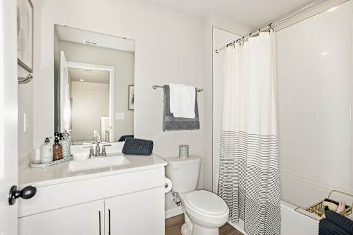 A white bathroom with a toilet, sink, and shower.