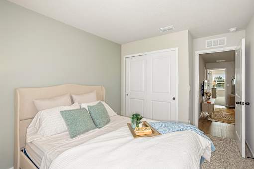 A bedroom with a large bed and a tray with a plant and a book on it.