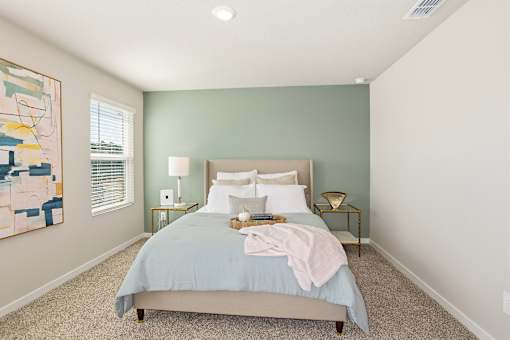 A bedroom with a bed, nightstands, and a painting on the wall.