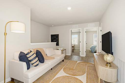 A living room with a white couch and a gold floor lamp.