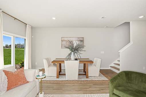 A living room with a white couch, a wooden dining table, and a green armchair.