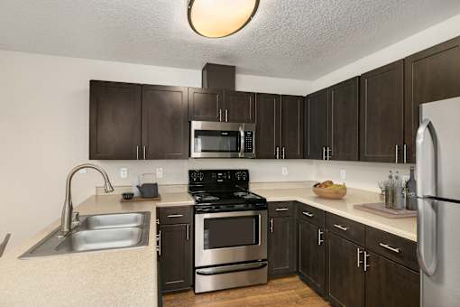 A kitchen with dark brown cabinets and stainless steel appliances
