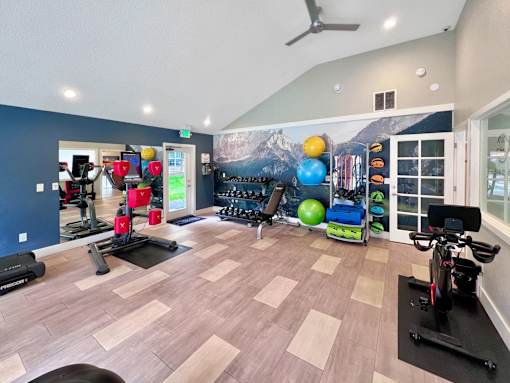 A gym with a variety of exercise equipment including treadmills, stationary bikes, and weights