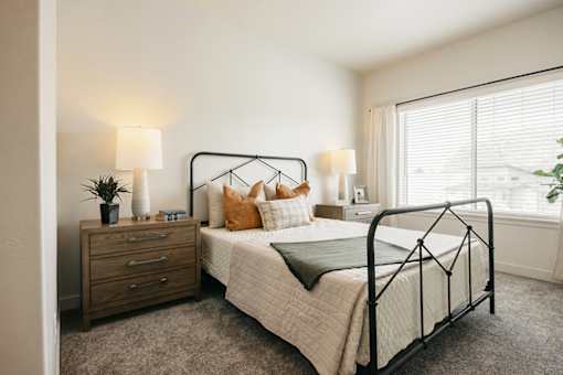 A bedroom with a bed, nightstand, and window.
