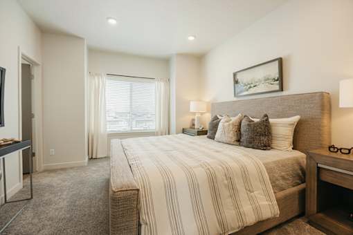 A well-lit bedroom with a large bed and a painting on the wall.