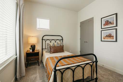 A bedroom with a bed, nightstand, and two pictures on the wall.