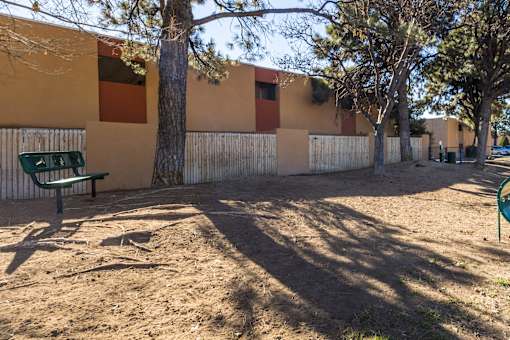A playground with a green bench and a fence.