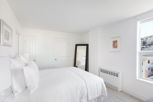 a white bedroom with a large window and a large bed