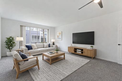 A living room with a white couch, a wooden coffee table, and a flat-screen TV.