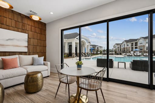 A modern living room with a view of a pool and houses outside.