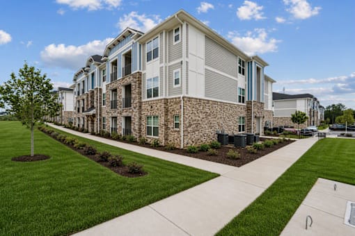 A modern apartment building with a well-maintained lawn in front.