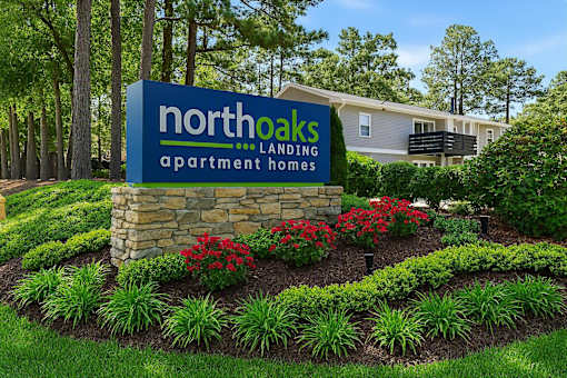A sign for Northoaks Apartment Homes is surrounded by a flower bed.