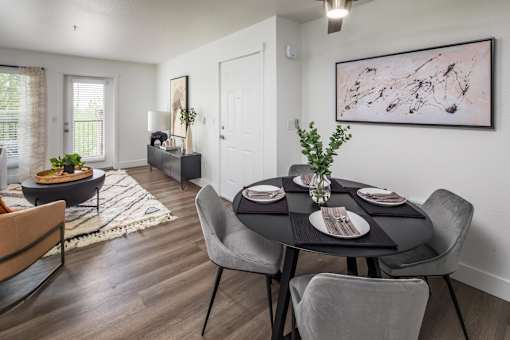 A dining room with a table set for two and a painting on the wall.