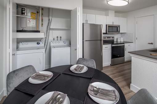 A modern kitchen with a black table set for two.