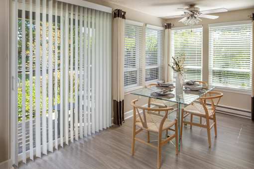 a dining room with white blinds and a table and chairs