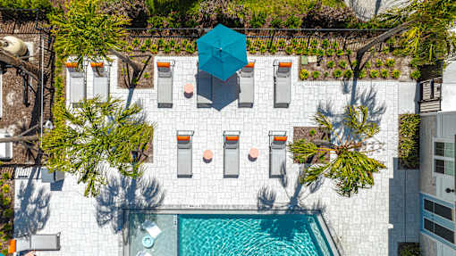 A blue umbrella is on a patio with a pool.