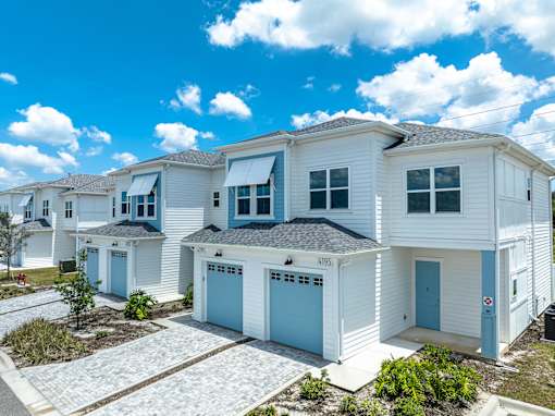 A row of white houses with blue garage doors.