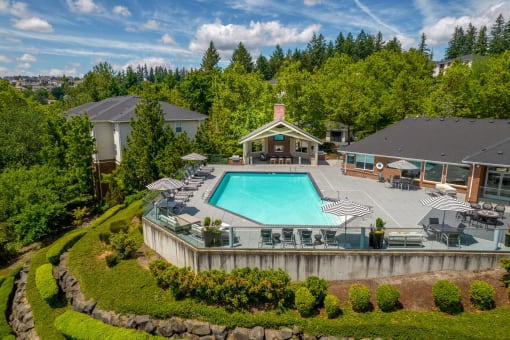 an aerial view of a resort style swimming pool with patio furniture and umbrellasat Arbor Heights, Tigard, Oregon
