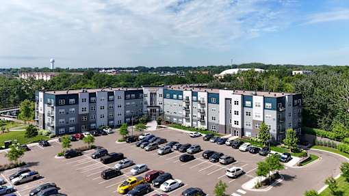A parking lot in front of a large apartment complex.