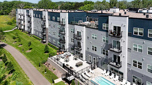 Apartment complex with a pool and a green lawn.