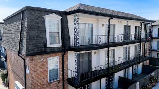A multi-story building with balconies and black railings.