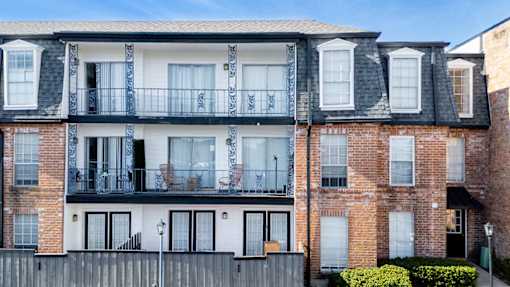 A large brick building with a balcony and a black railing.
