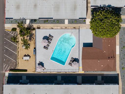 An aerial view of a pool surrounded by chairs and umbrellas.