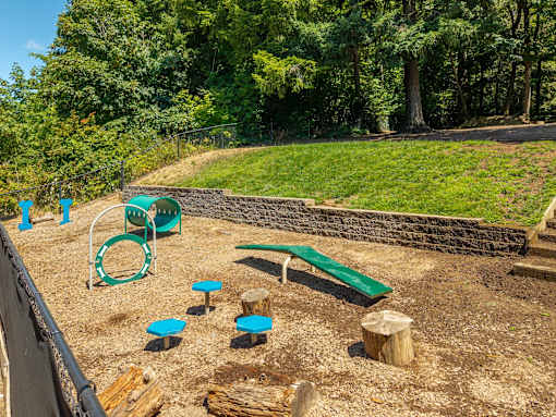 A playground with a green slide, a wooden log, and a green bench.