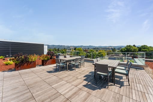 the deck on the roof of a building with tables and chairs