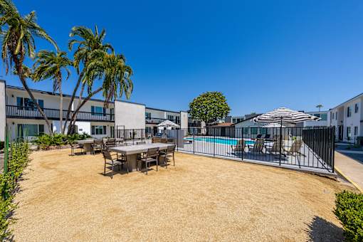 A sunny day at the poolside with a table and chairs set up.