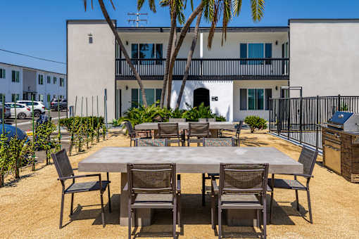 A table surrounded by chairs is in the middle of a courtyard.