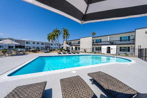 A swimming pool with sun loungers and a building in the background.