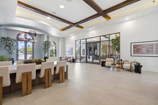 A room with a long table and chairs with a view of the outside.