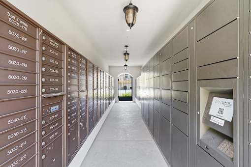 A long hallway with mailboxes on the wall and a light hanging from the ceiling.