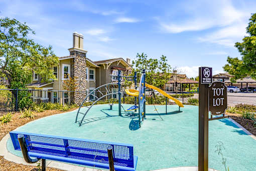 A playground with a blue slide and a sign that says "TOT LOT".
