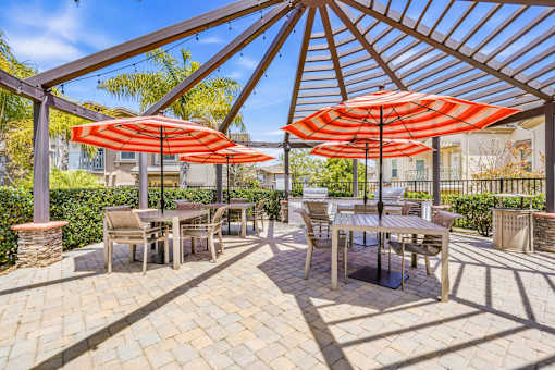 A patio with tables and chairs under umbrellas.