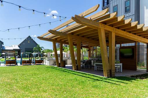A wooden pergola is in the foreground of a sunny day.