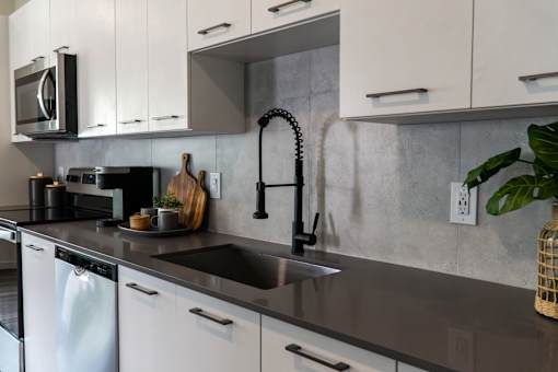 A modern kitchen with a black faucet and white cabinets.