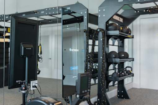 A gym with a mirror, weight rack and weights.